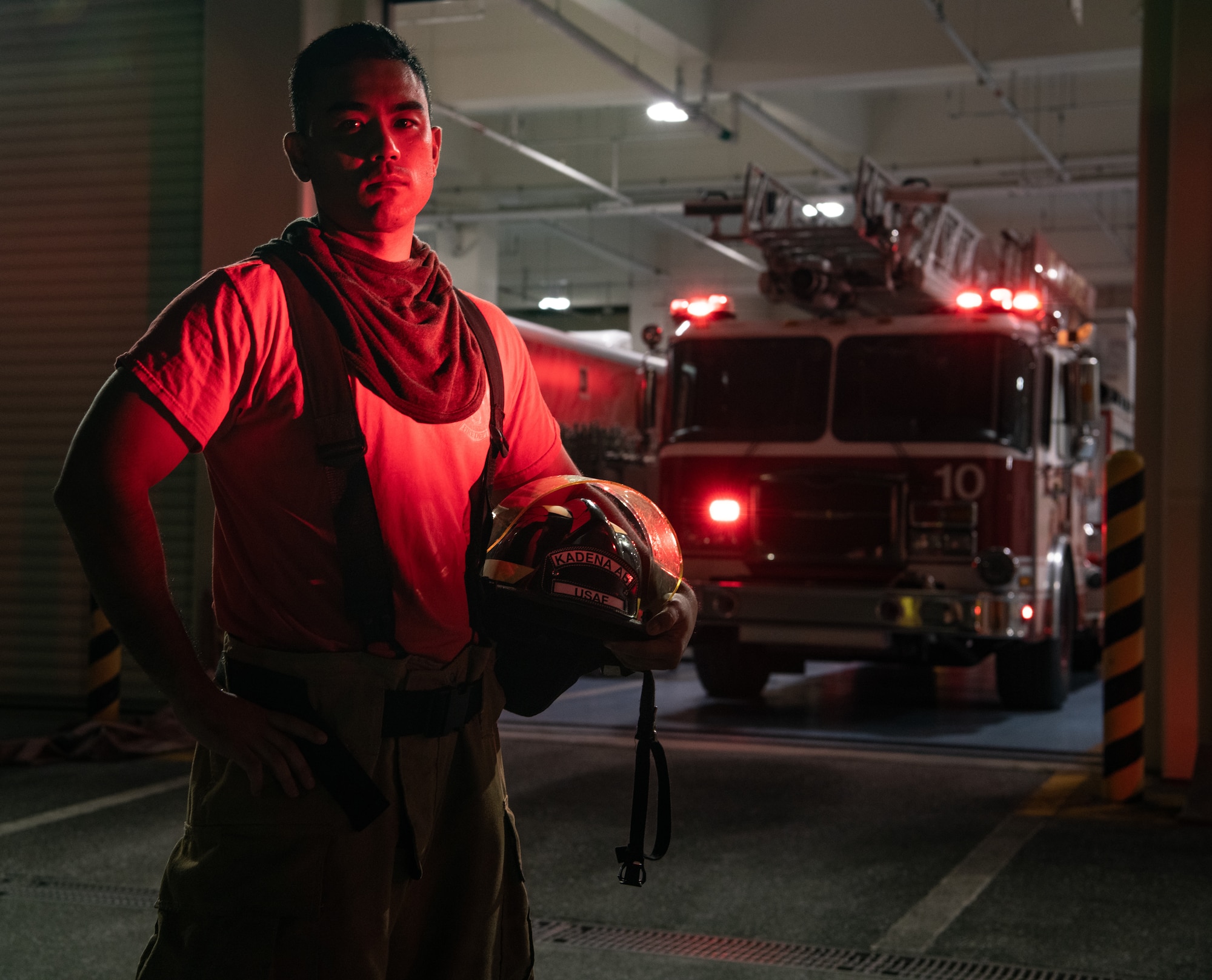 A civilian firefighter stands in front of a fire truck.