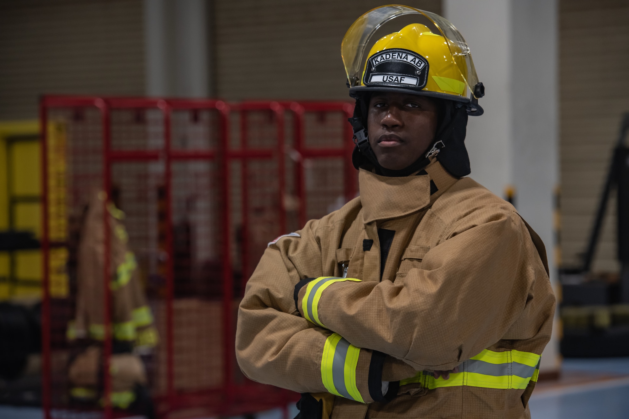An Airman standing in bunker gear in the bay of a fire station.