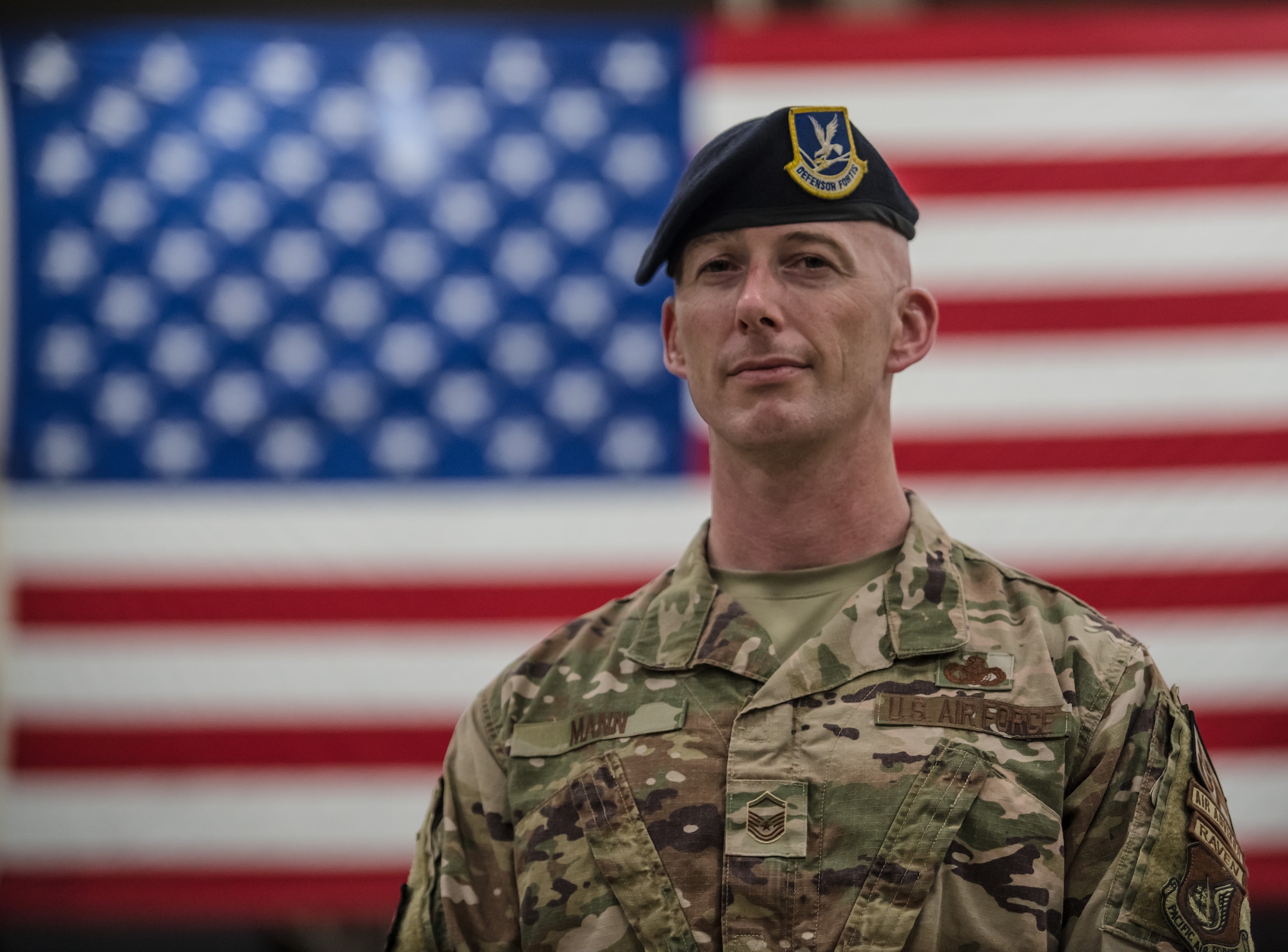 An Airman standing in front of an American Flag.