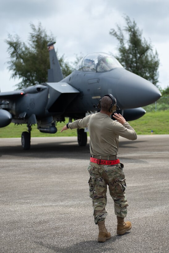 A U.S. Air Force Airmen guides a F-15E Strike Eagle on a Flight Line to park it