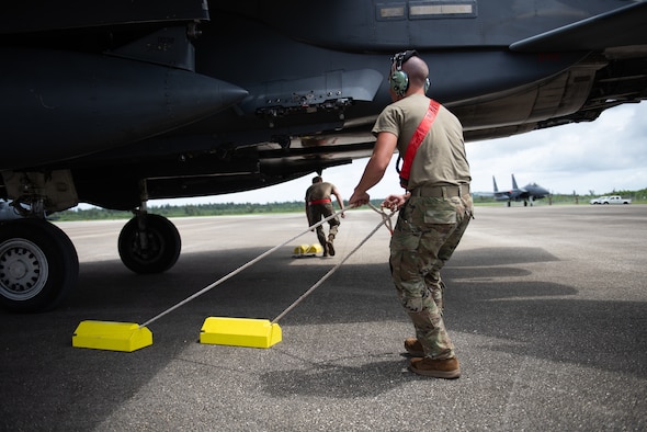 A U.S. Air Force Airmen pulls yellow chocks from underneath an F-15E Strike Eagle