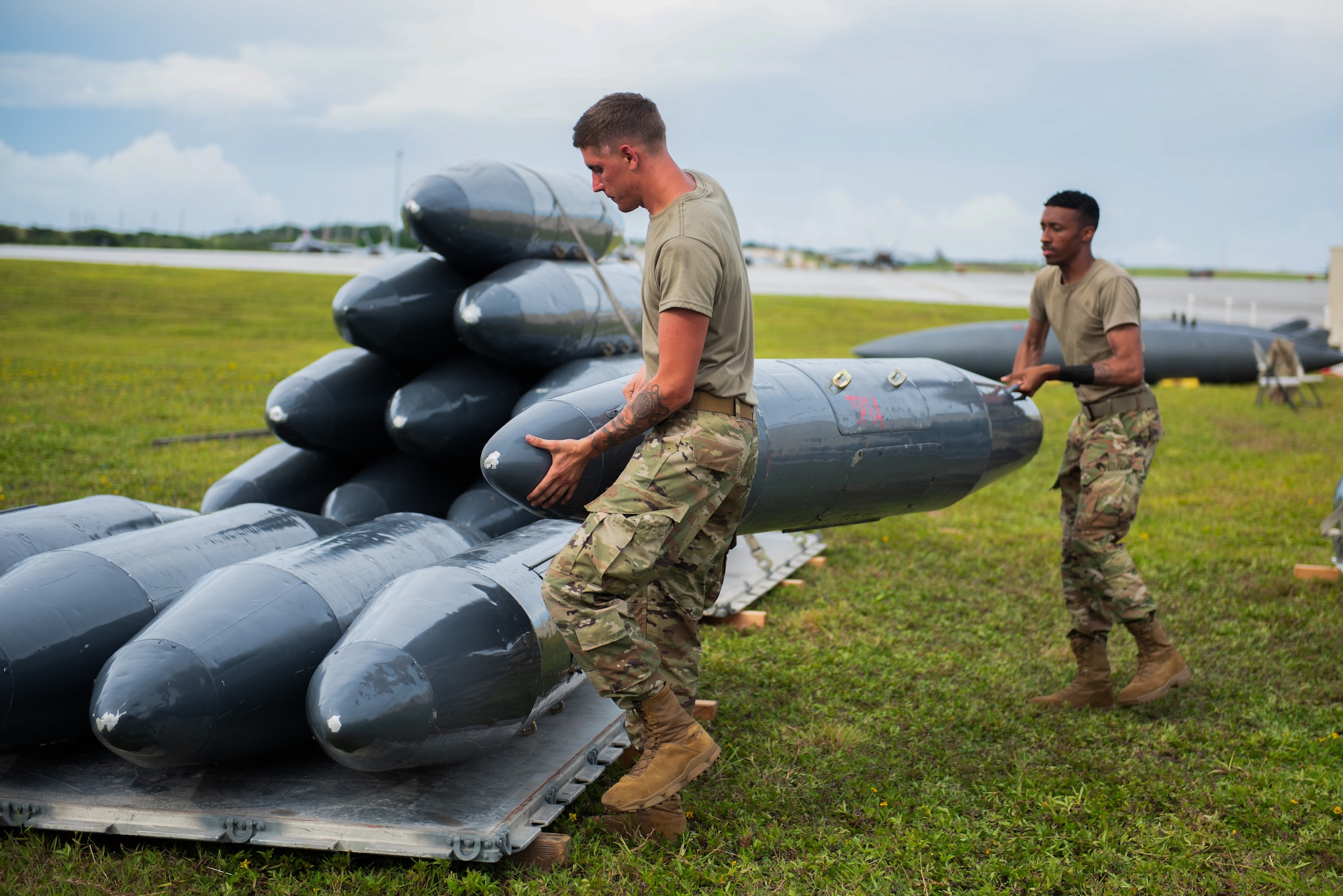 Two U.S. Air Force Airmen stack travel pods for an F-15E Strike Eagle on a pallet to be stored