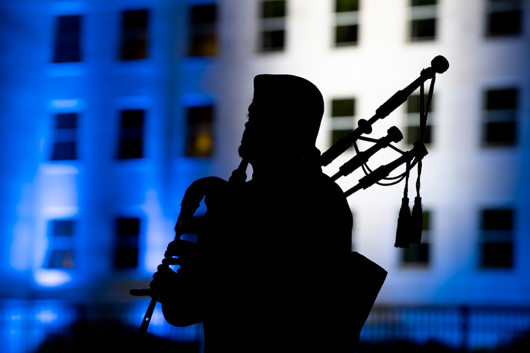 The silhouette of a bagpipe player in front of the Pentagon.