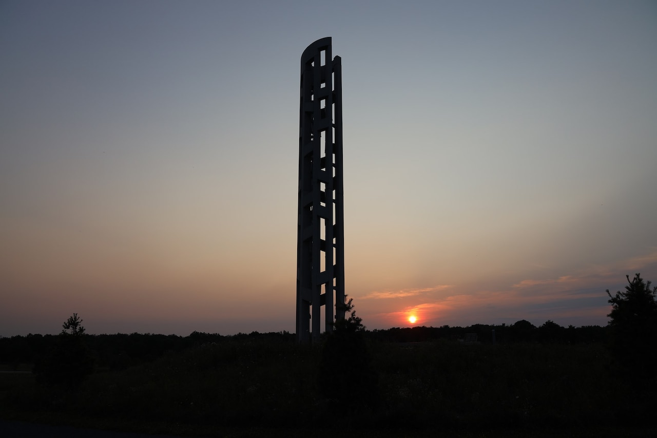 The silhouette of a memorial with a sunrise in the background.