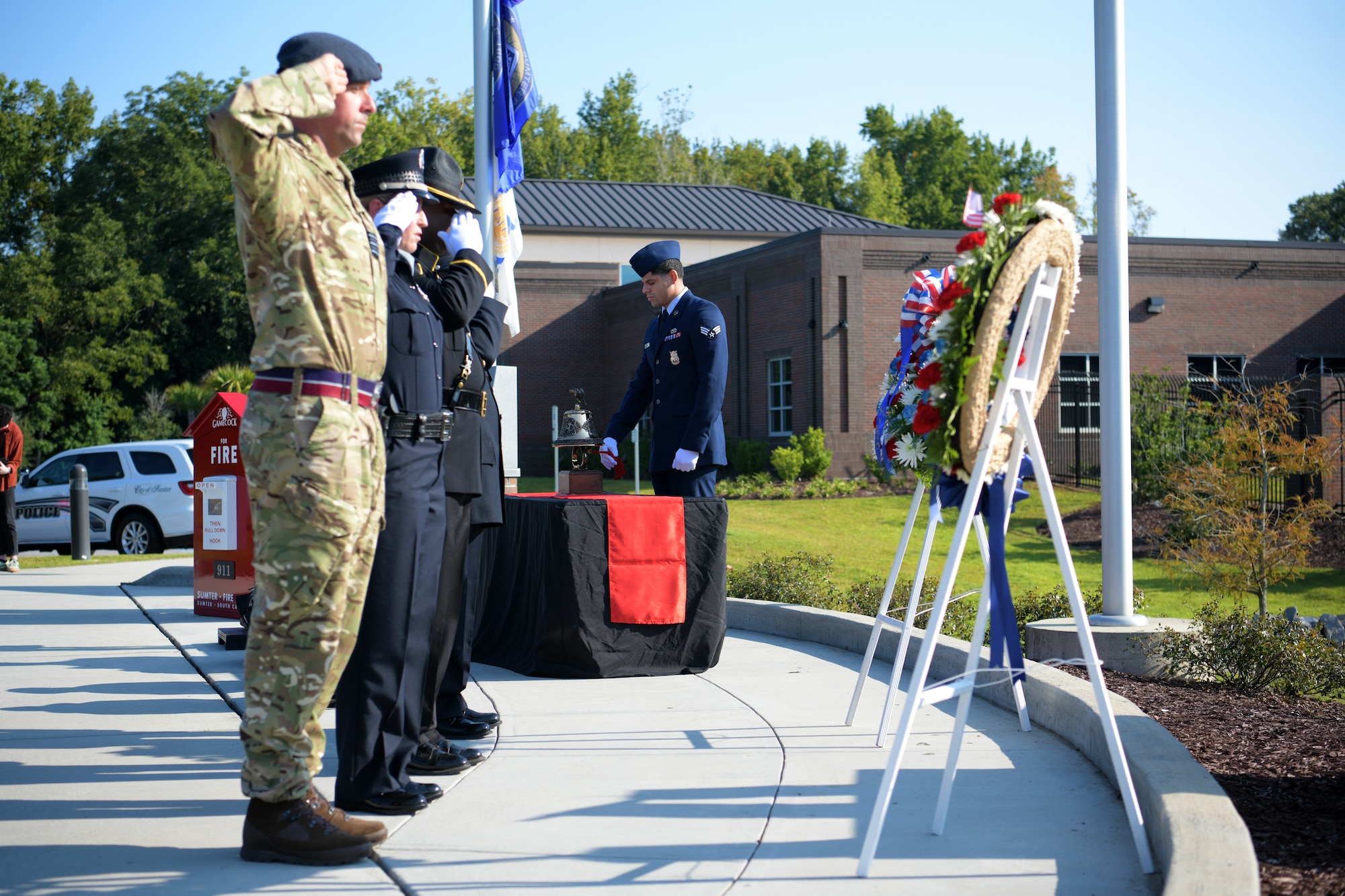 Members of a joint honor guard from Sumter first responders and Royal Air Force salute wreaths while an Airman assigned to the 20th Civil Engineer Squadron rings a bell during a 9/11 memorial ceremony in Sumter, S.C., Sept. 11, 2021. The ceremony was held in remembrance of the 20th anniversary of the Sept. 11, 2001, attacks across the United States. (U.S. Air Force photo by Staff Sgt. K. Tucker Owen)