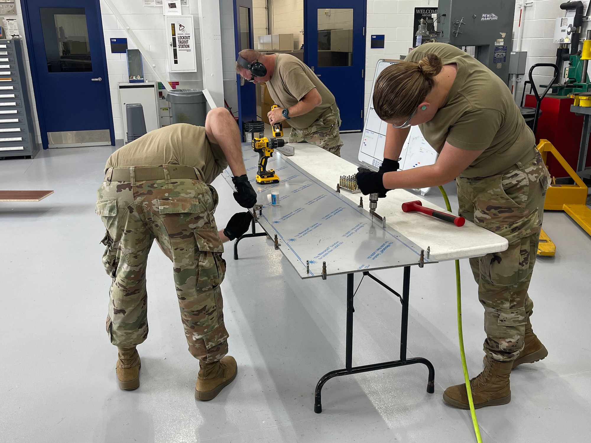 Airmen assigned to the 157th Air Refueling Wing drill holes in a piece of sheet metal at Pease Air National Guard Base, New Hampshire, Sept. 1, 2021. The sheet metal was used to make the twin tower memorial structure. (Courtesy photo)