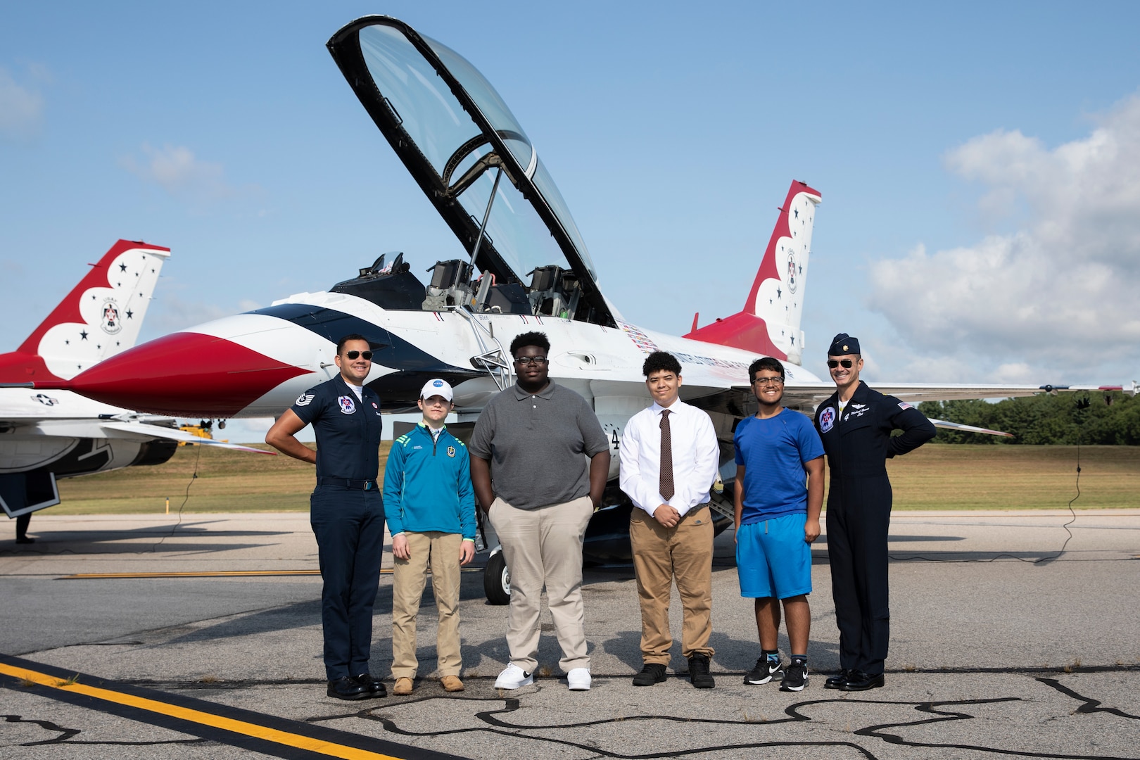 (From left to right) Tech Sgt. Peter Rivera, United States Air Force Air Demonstration Squadron "Thunderbirds”, Zachory Durham, Tyler Harris, James Connolly, Max Saravia, and Maj. Michael Brewer, United States Air Force Air Demonstration Squadron "Thunderbirds”, pose for a photo at the 2021 Thunder Over New Hampshire Airshow Open House on Pease Air National Guard Base, Portsmouth, New Hampshire, Sept. 10, 2021. Brewer and Rivera gave a tour of their F-16 Fighting Falcon to a small group of people before starting their aerial performance show. (U.S. Army National Guard photo by Devin Bard)