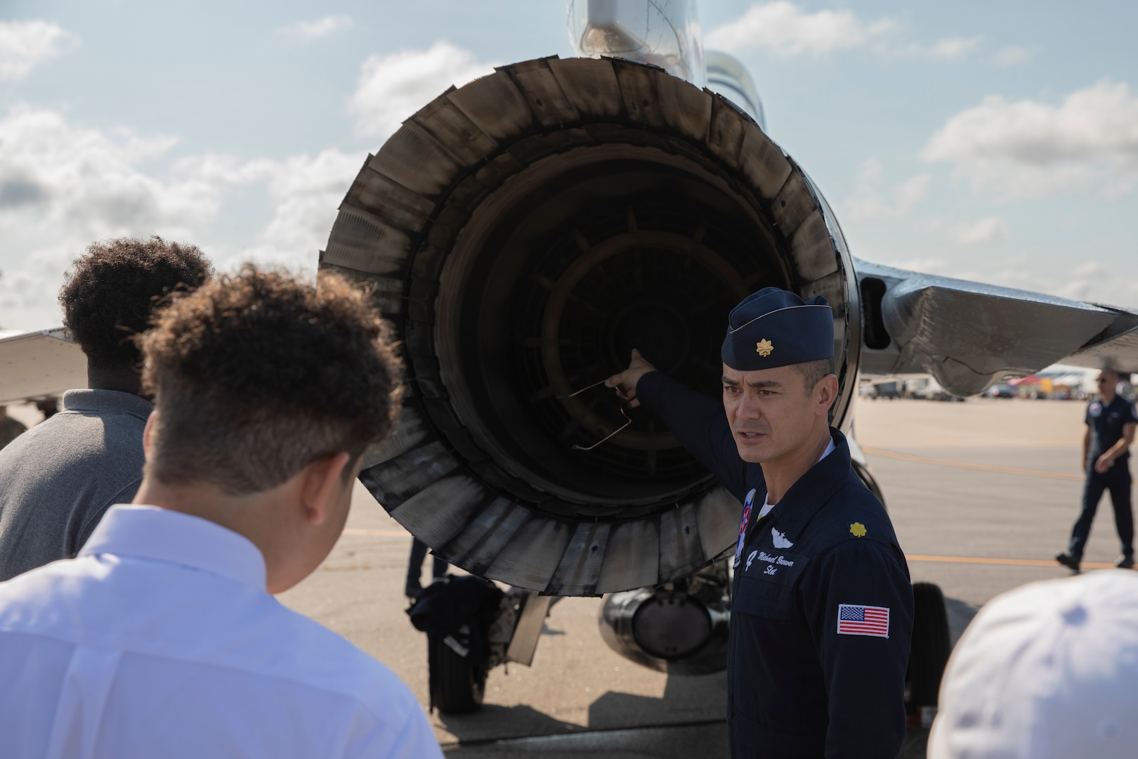 Maj. Michael Brewer, United States Air Force Air Demonstration Squadron "Thunderbirds” slot 4 pilot, teaches a small group about the F-16 Fighting Falcon exhaust system at the 2021 Thunder Over New Hampshire Airshow Open House, Pease Air National Guard Base, Portsmouth, New Hampshire, Sept. 10, 2021. The 2021 Thunder Over New Hampshire Airshow Open House is the first open house air show at Pease Air National Guard Base in over a decade. (U.S. Army National Guard photo by Devin Bard)