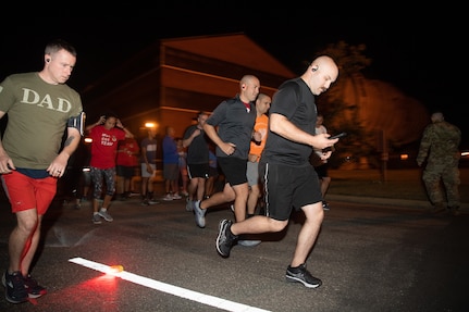 A group of Airmen walk and run outside in an event.