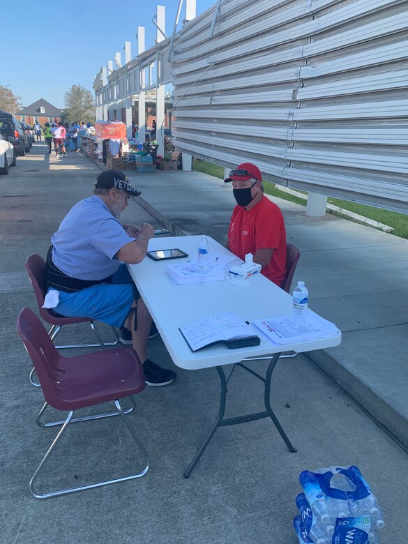 Jason Eisenhower, a U.S. Army Corps of Engineers employee working in Louisiana as part of the Hurricane Ida recovery effort, assists a local resident fill out a right of entry form for the Blue Roof Program.