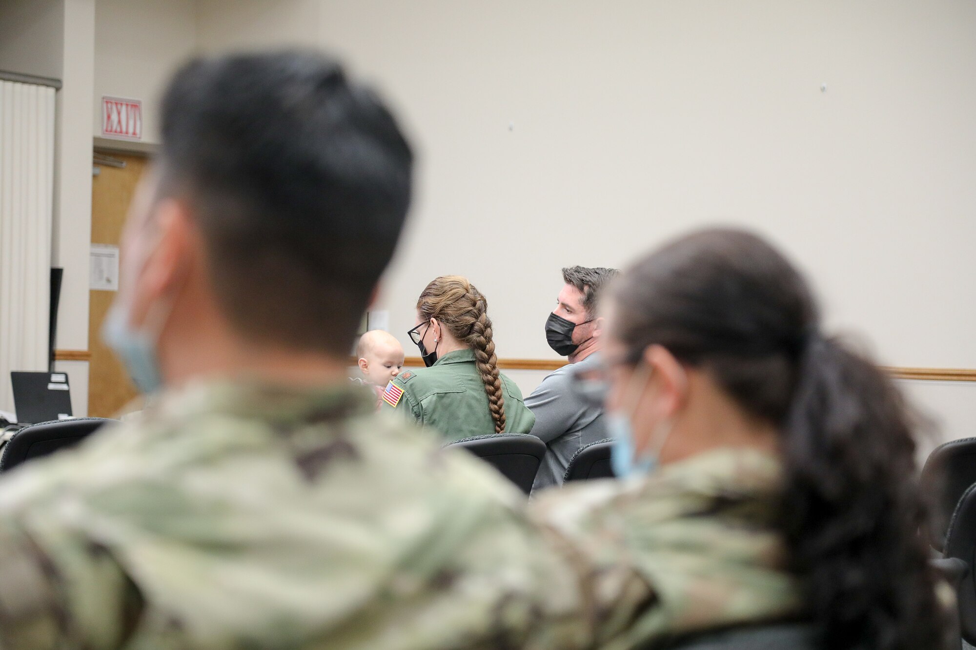 Airman sits with baby in auditorium