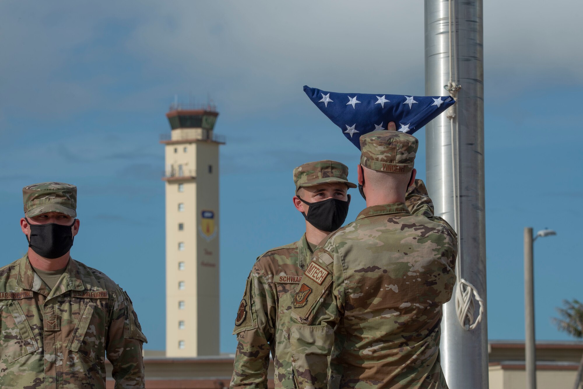 Airmen inspecting a folded flag during a ceremony.