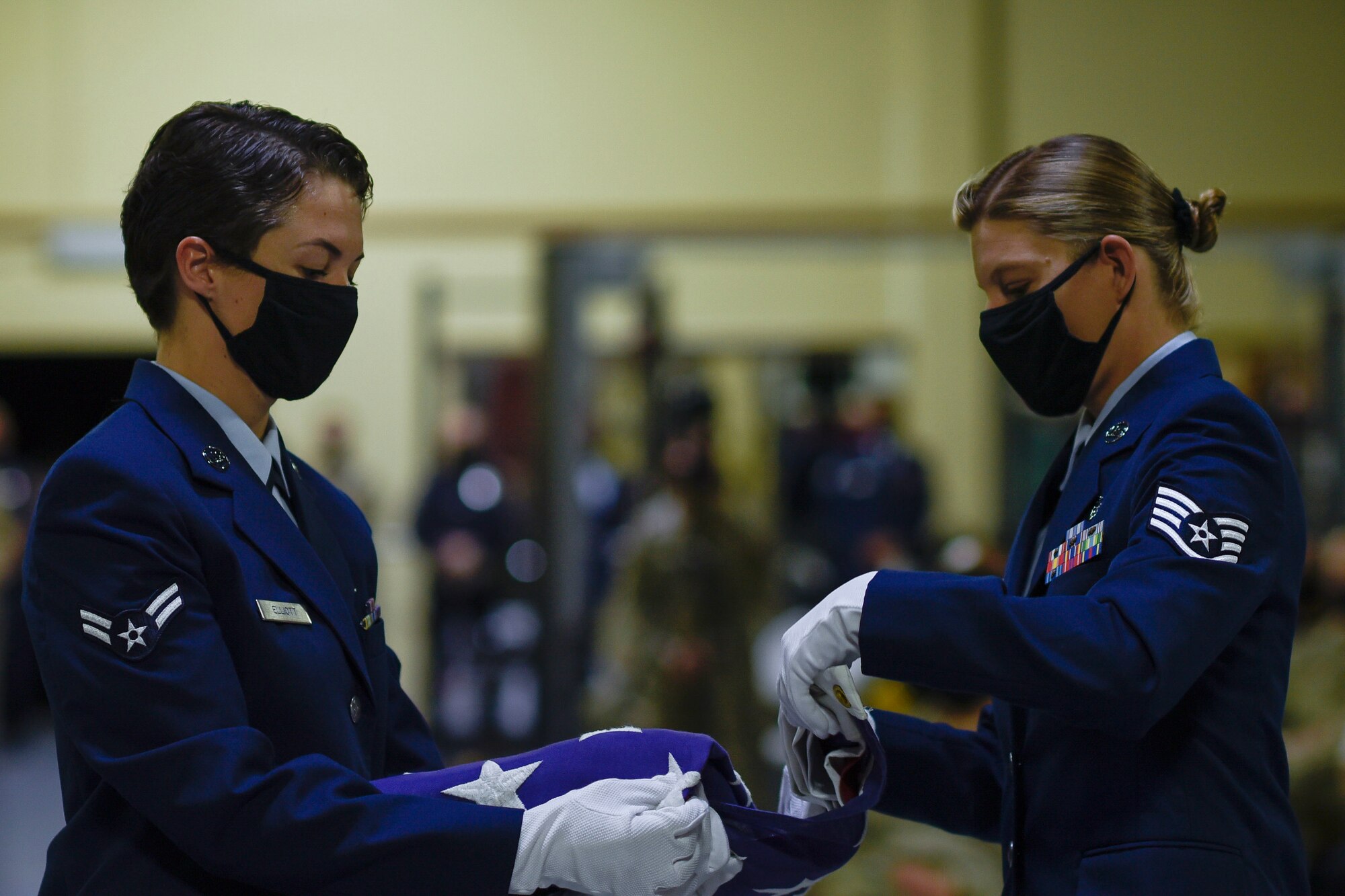 Two Airmen folding a flag.