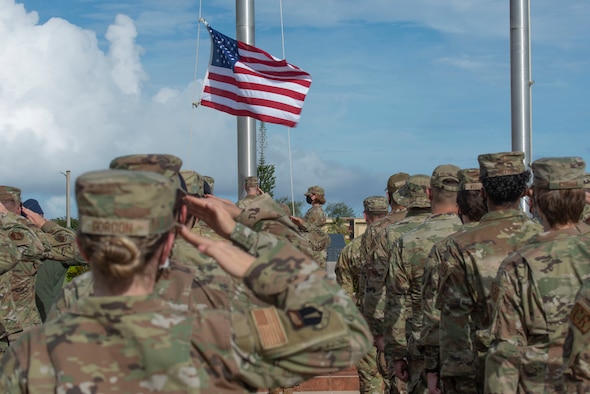 Two airmen fold a flag during a ceremony.