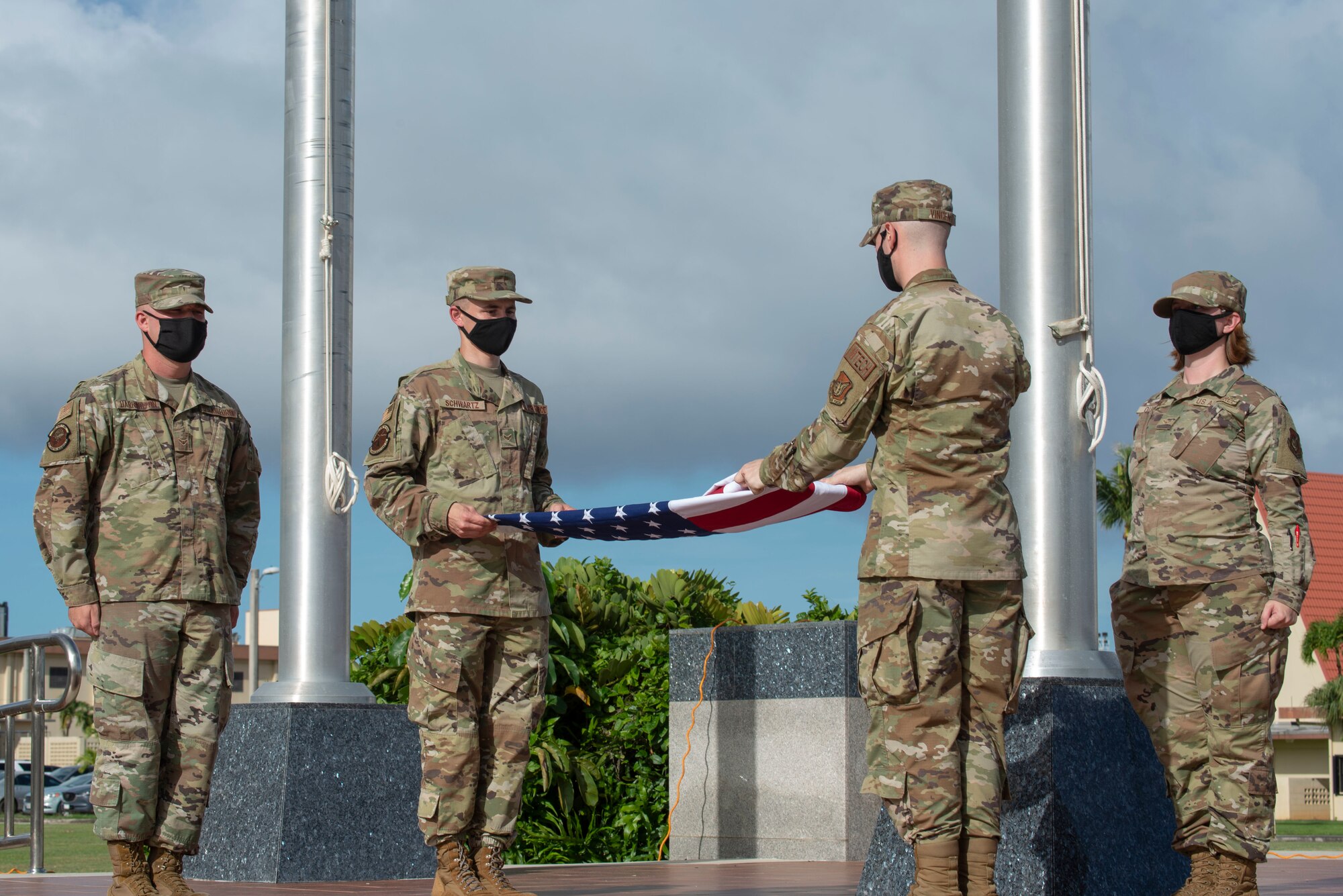 Two airmen fold a flag during a ceremony.