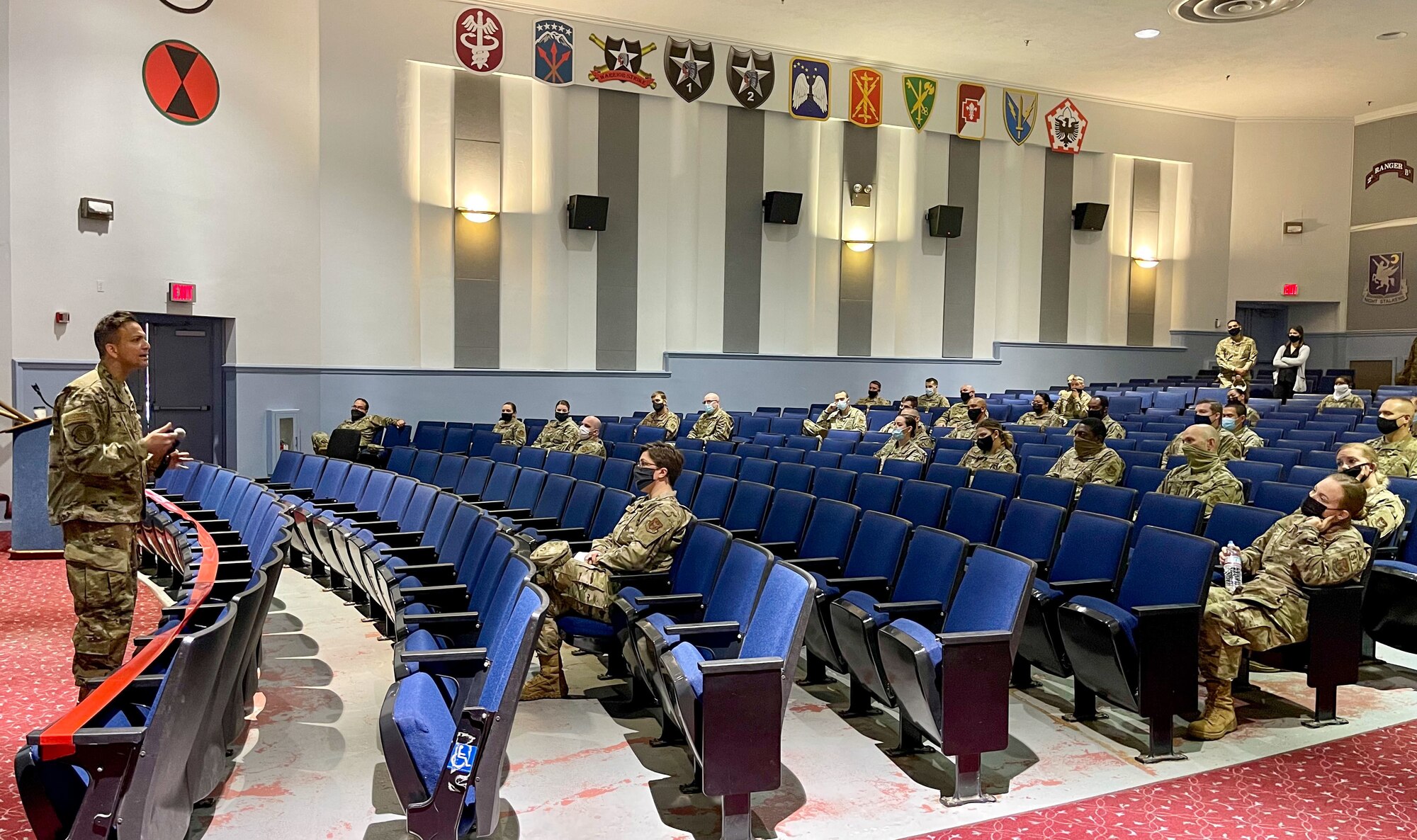 Military doctor speaks to Airmen in an auditorium
