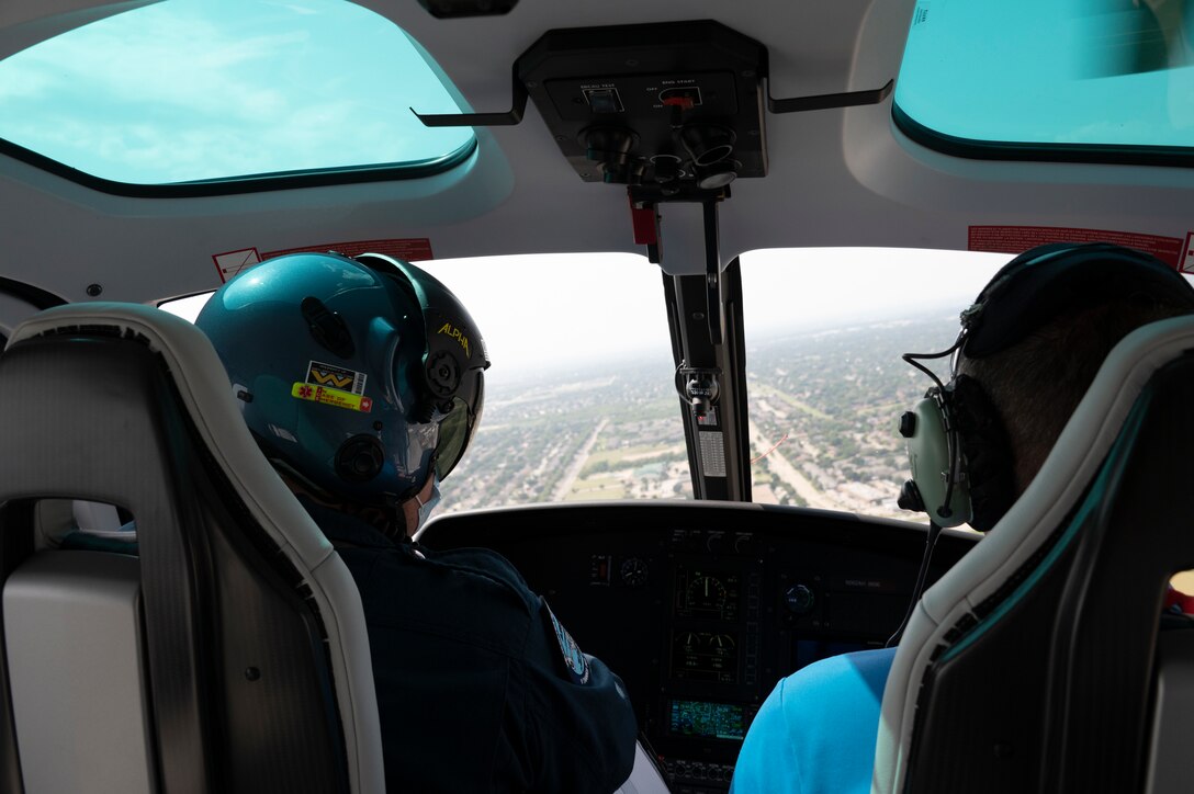 Two people sit inside a helicopter.