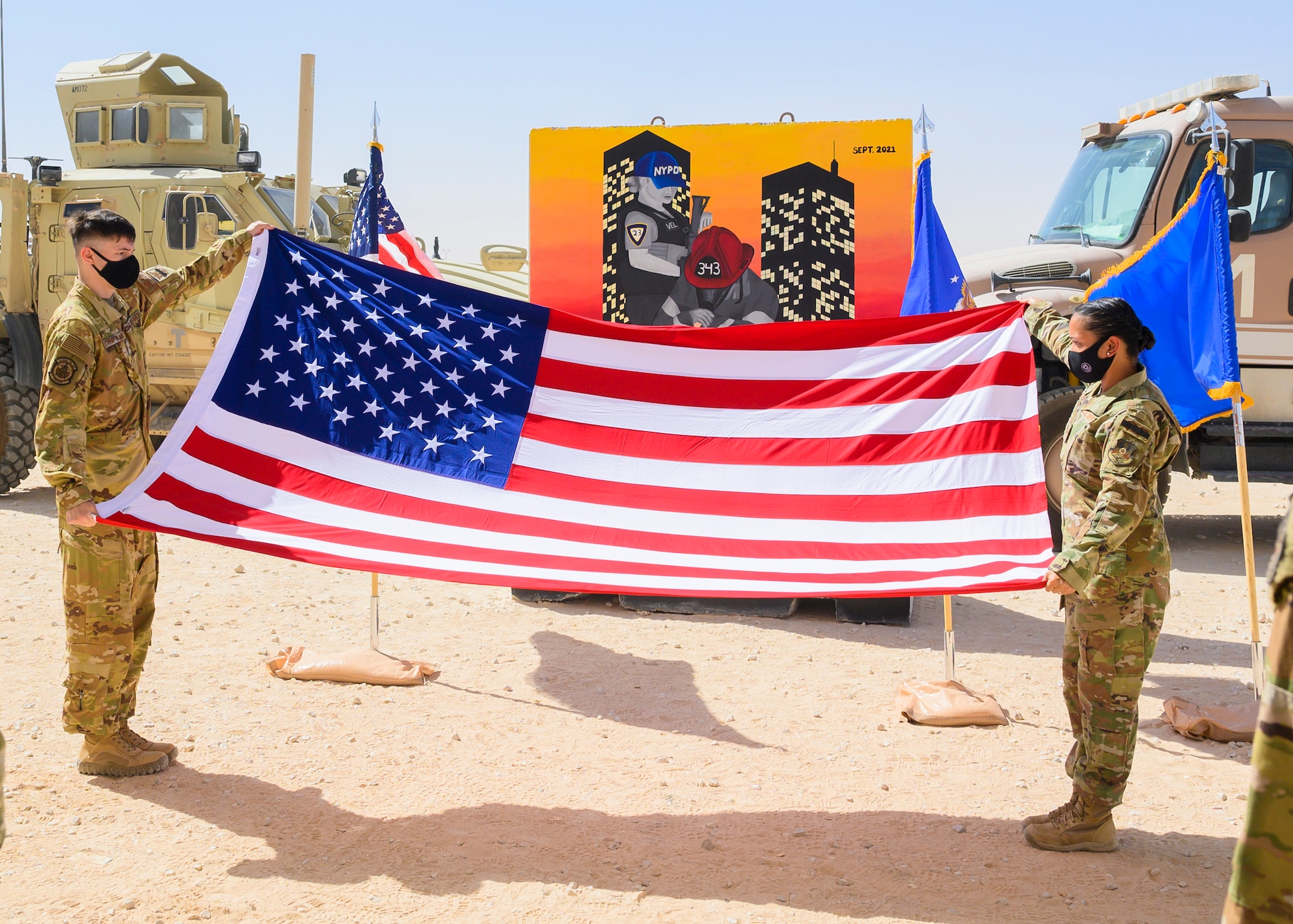 Airman 1st Class Timothy Treat-Mass, 378th Expeditionary Civil Engineer Squadron firefighter, and Staff Sgt. Aubrey Houston, 378th Expeditionary Security Forces Squadron defender, prepare to fold the flag during a Remembrance Ceremony Sept. 11, 2021, at Prince Sultan Air Base, Kingdom of Saudi Arabia.