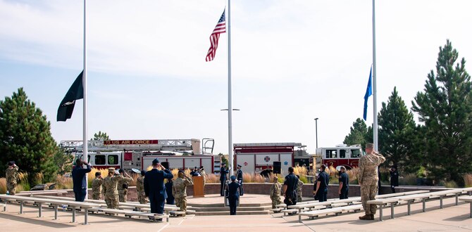 Members participating in the Patriot Day 9/11 ceremony render a salute as the American flag is lowered at Buckley Space Force Base, Colo., Sept. 10, 2021.