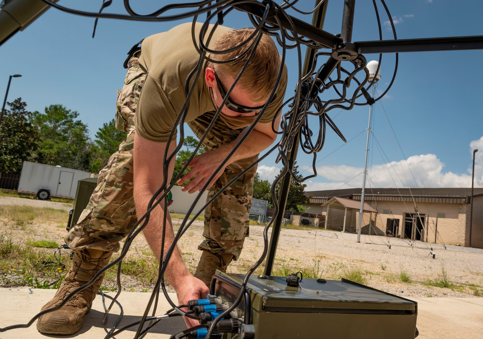 An airman loosens power cables on a tactical meteorological observing system