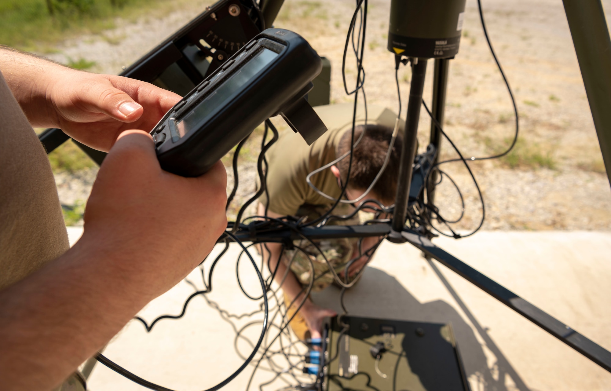 An airman tightens power cables on a tactical meteorological observing system