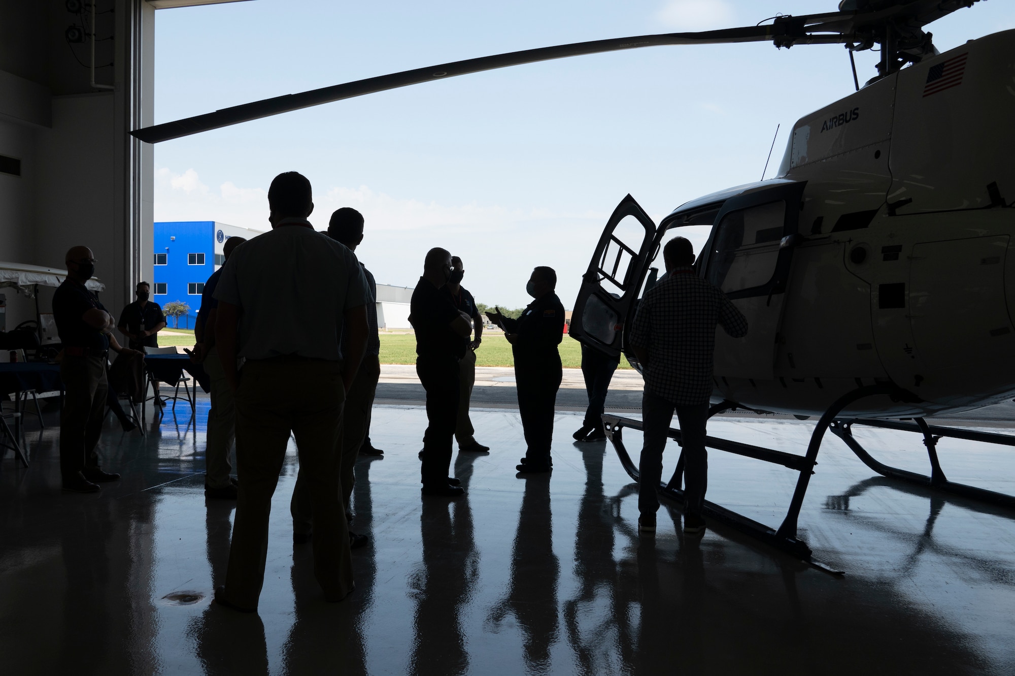 A group of people stand near a H-125 helicopter.
