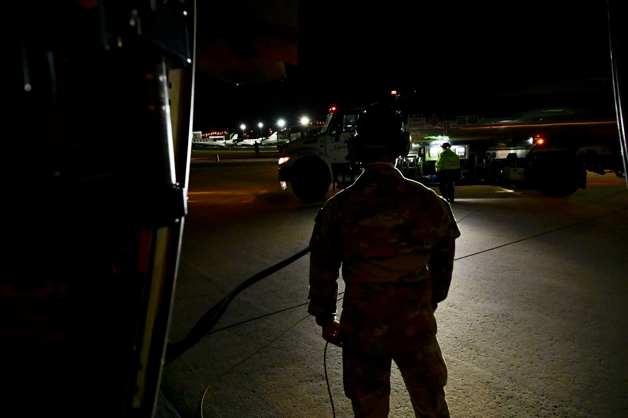 An Airmen watches as a C-130J is refueled