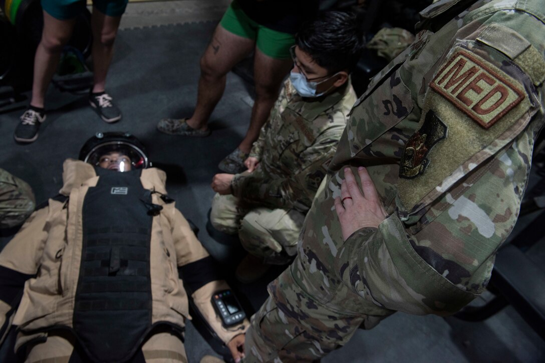 Airmen look at a bomb suit