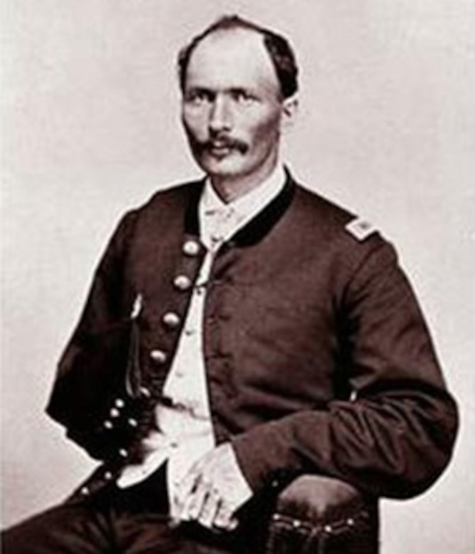 A soldier in a Civil War-era uniform sits for a photo.