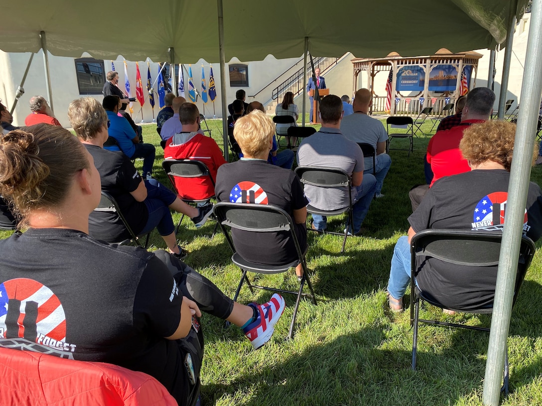 Seated individuals listen to speech during a 9/11 ceremony