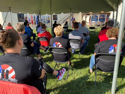 Seated individuals listen to speech during a 9/11 ceremony
