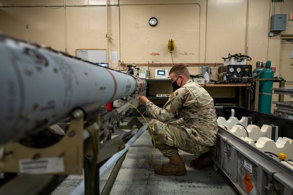 Man kneeling beside a missile