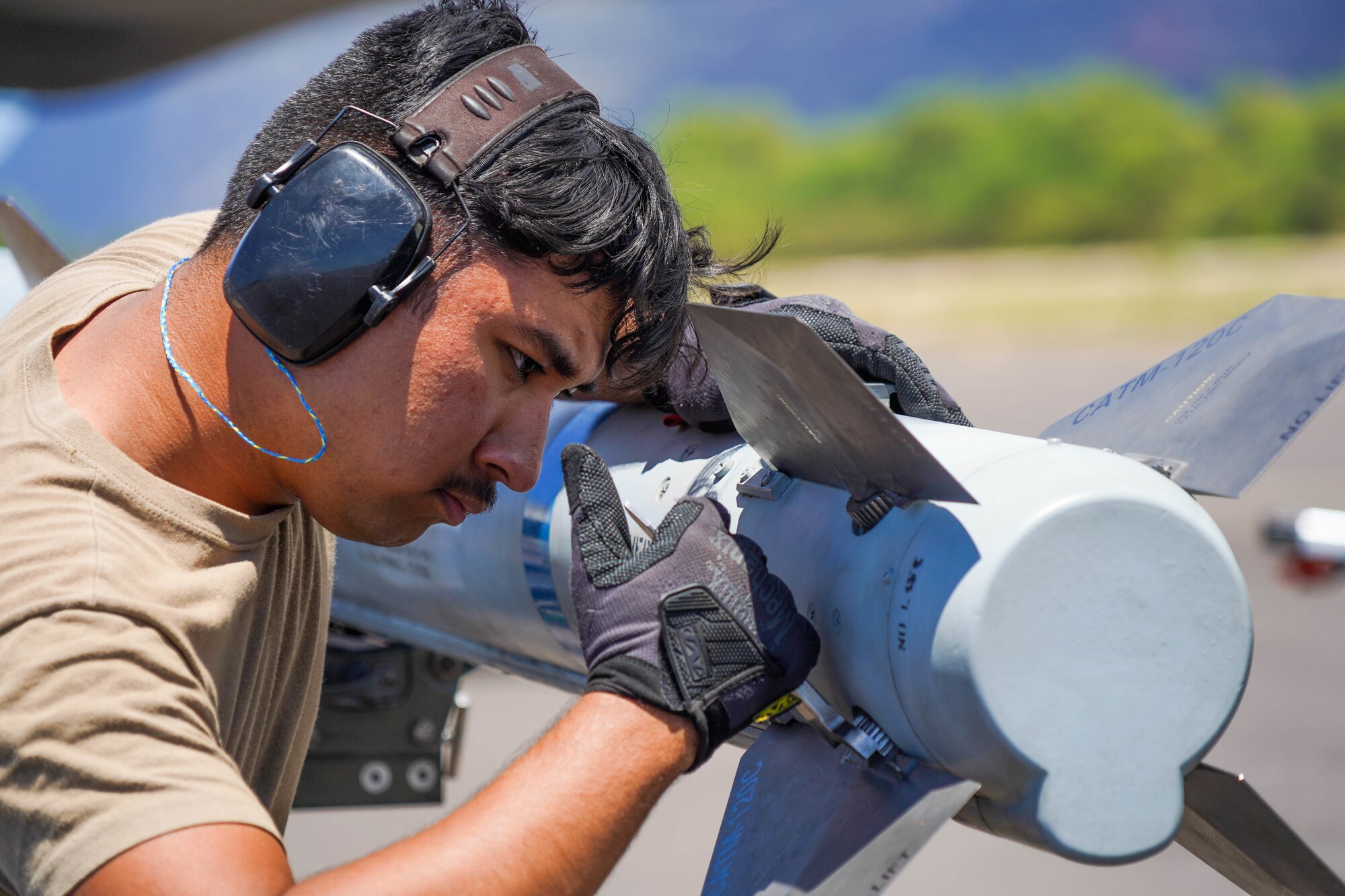 Senior Airman Paulo Amaya, 15th Aircraft Maintenance Squadron weapons load crew member,  tightens a fin on a Captive Air Training Missile AIM-120 during an Agile Combat Employment training exercise at Pacific Missile Range Facility Barking Sands, Hawaii, September 8, 2021. The ACE concept utilizes Multi-Capable Airmen to refuel, rearm, and perform maintenance to fighter jets ensuring the aircraft are ready to rapidly deploy. (U.S. Air Force photo by Airman 1st Class Makensie Cooper)