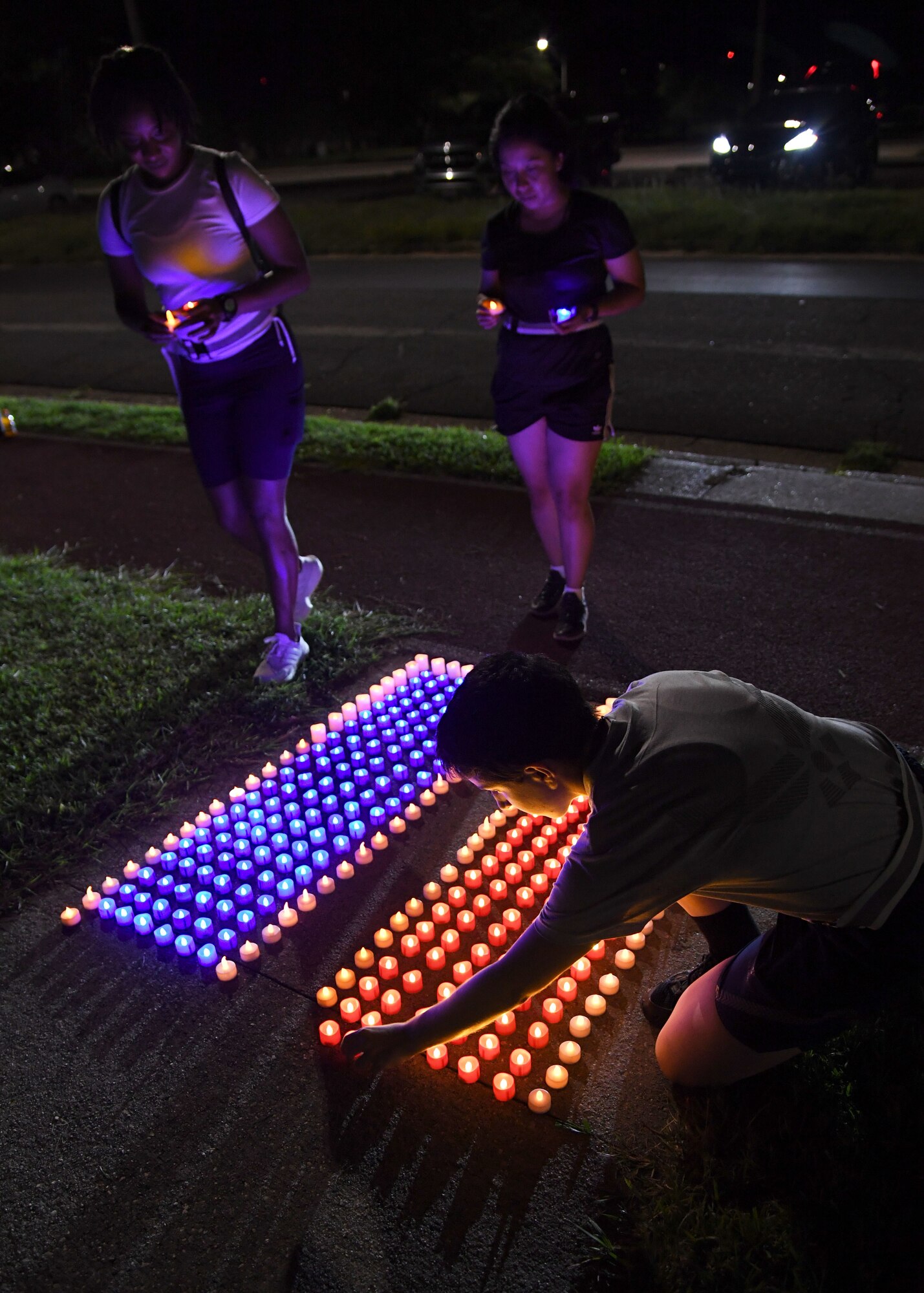 U.S. Air Force Airman 1st Class Halimatou Diallo and Airman Karla Monroy, 335th Training Squadron students, and Airman 1st Class Emily Kalman, 338th Training Squadron student, place flameless candles on the ground outside of Stennis Hall during the 2nd Annual 9/11 Memorial Run at Keesler Air Force Base, Mississippi, Sept. 10, 2021. The 24-hour run honored those who lost their lives during the 9/11 attacks. (U.S. Air Force photo by Kemberly Groue)