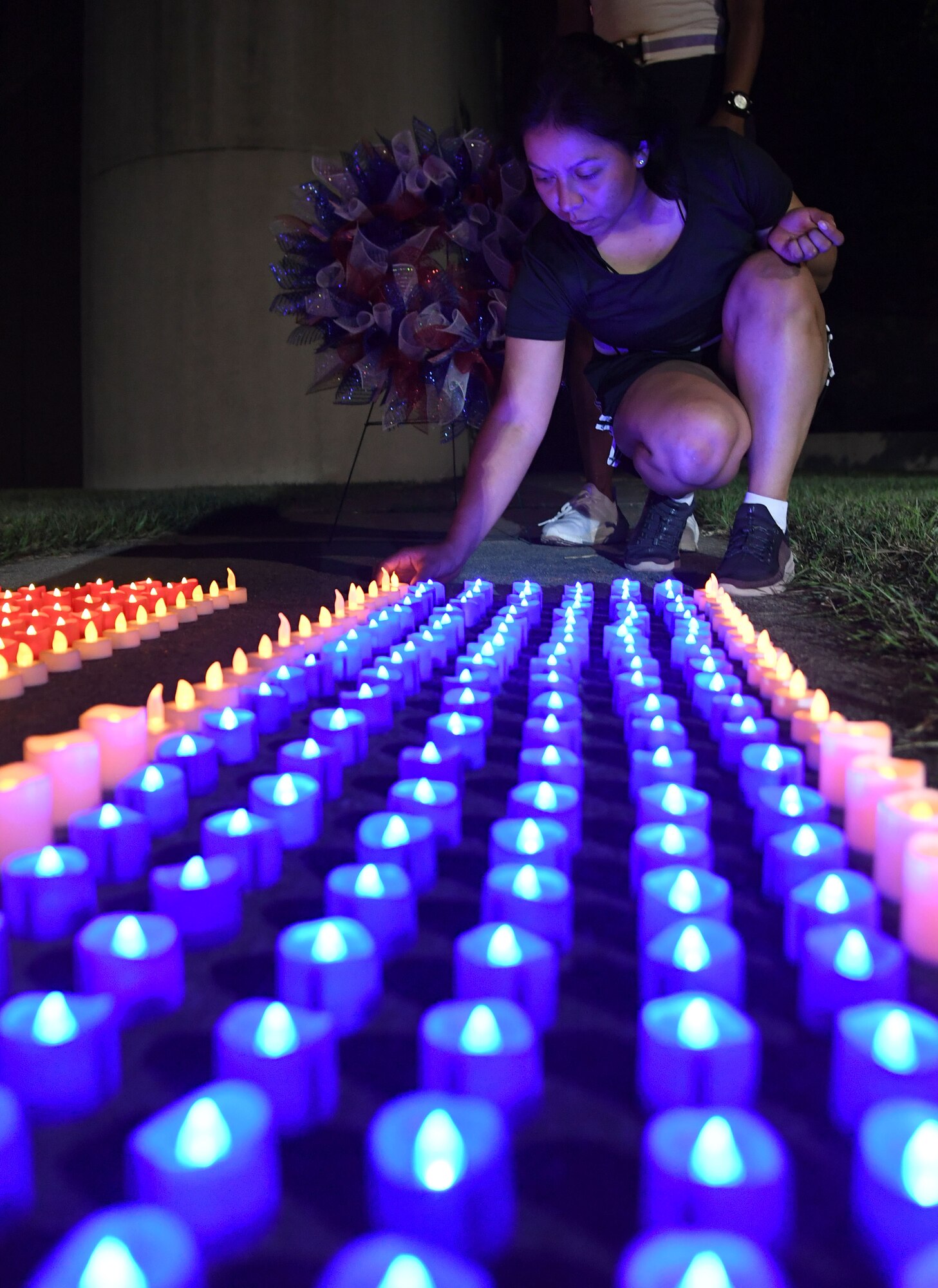 U.S. Air Force Airman Basic Karla Monroy, 335th Training Squadron student places a flameless candle on the ground outside of Stennis Hall during the 2nd Annual 9/11 Memorial Run at Keesler Air Force Base, Mississippi, Sept. 10, 2021. The 24-hour run honored those who lost their lives during the 9/11 attacks. (U.S. Air Force photo by Kemberly Groue)
