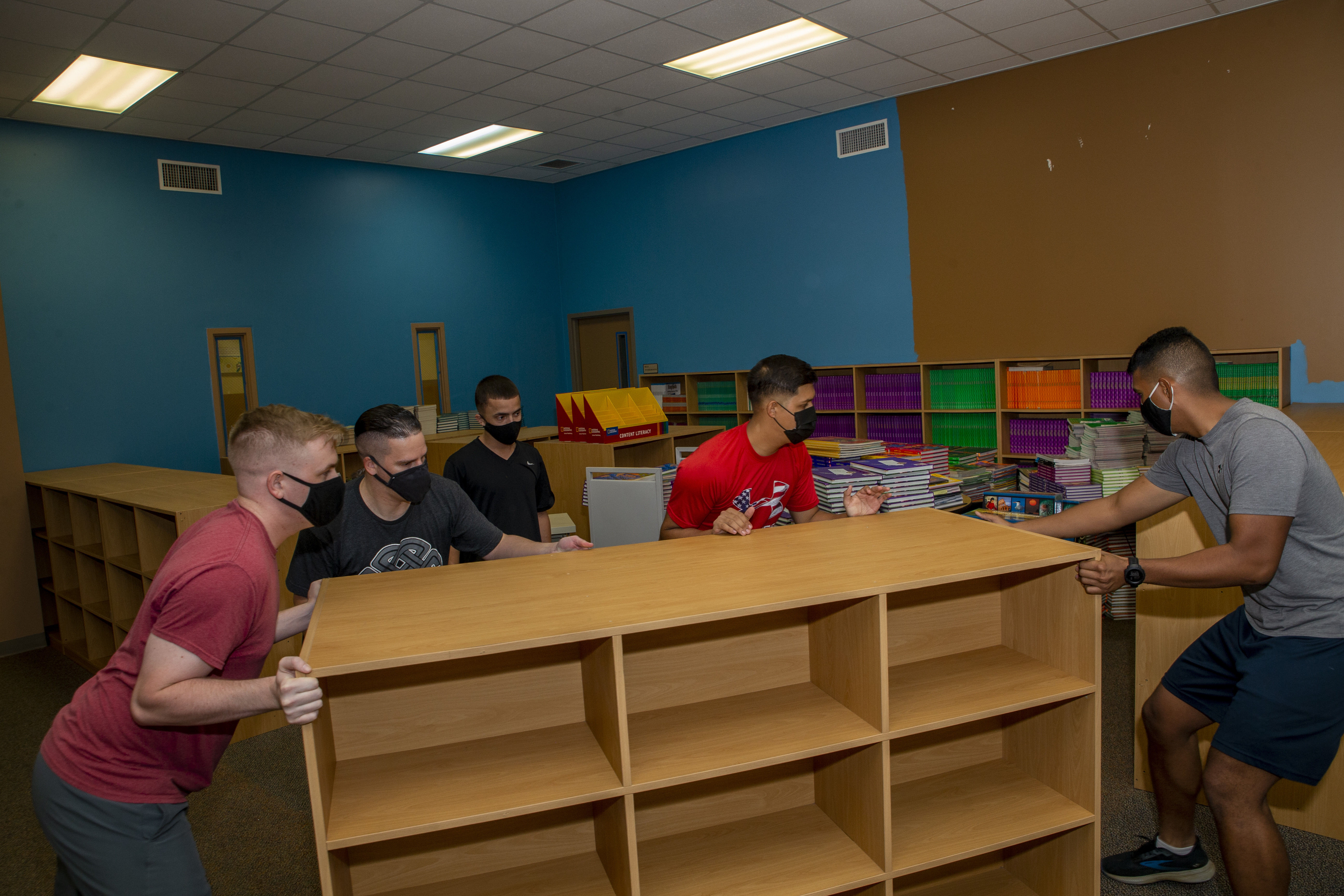 Marines assigned to Marine Corps Base Camp Blaz move bookshelves during a volunteer event at Liguan Elementary School in Dededo, Guam, Sept. 10, 2021.