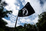 A flag flies against a blue sky with white clouds.