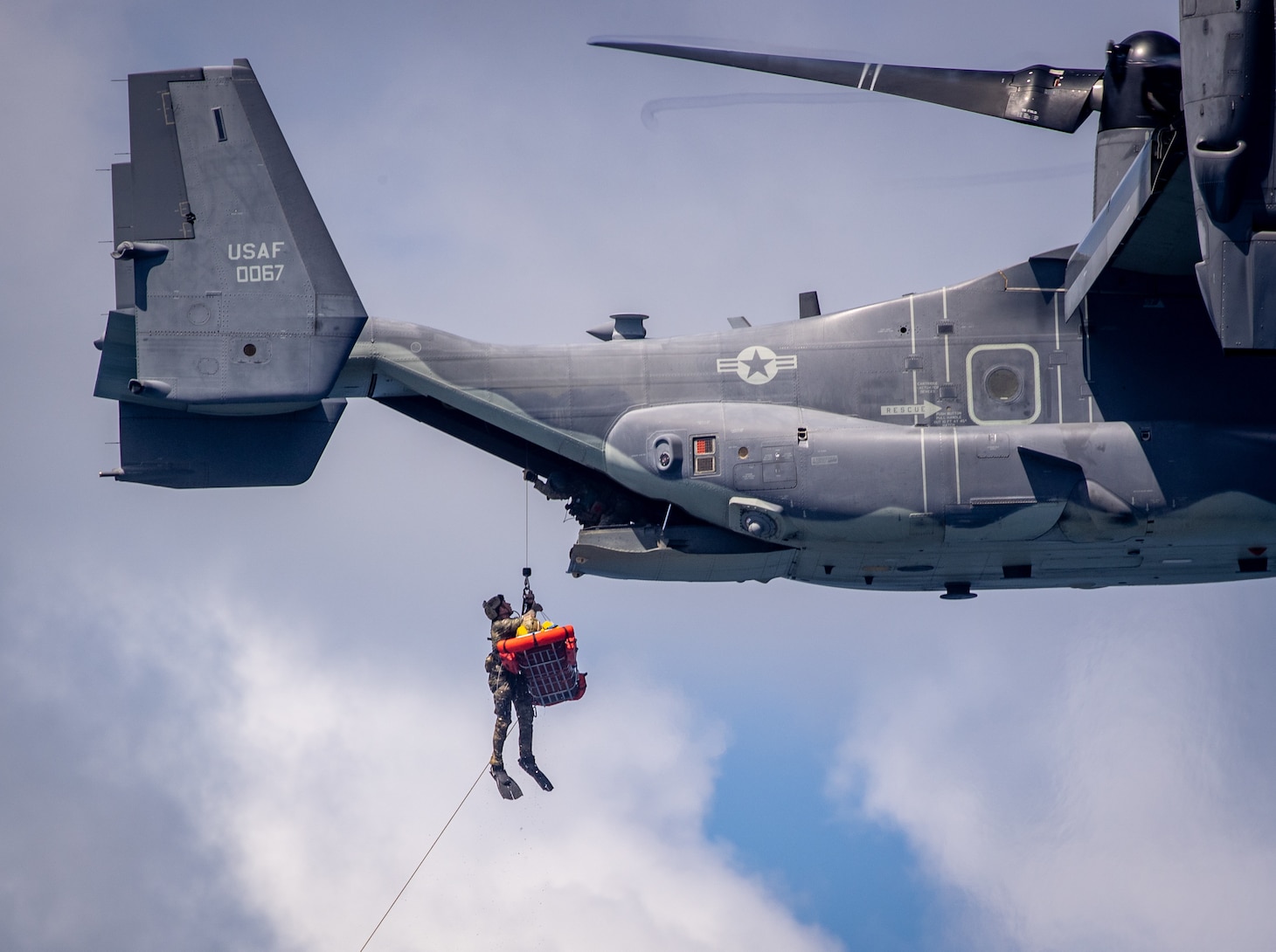 A U.S. Naval Special Warfare (NSW) operator conducts a medical evacuation hoist during interoperability training with a 353rd Special Operations Wing CV-22 Osprey.
