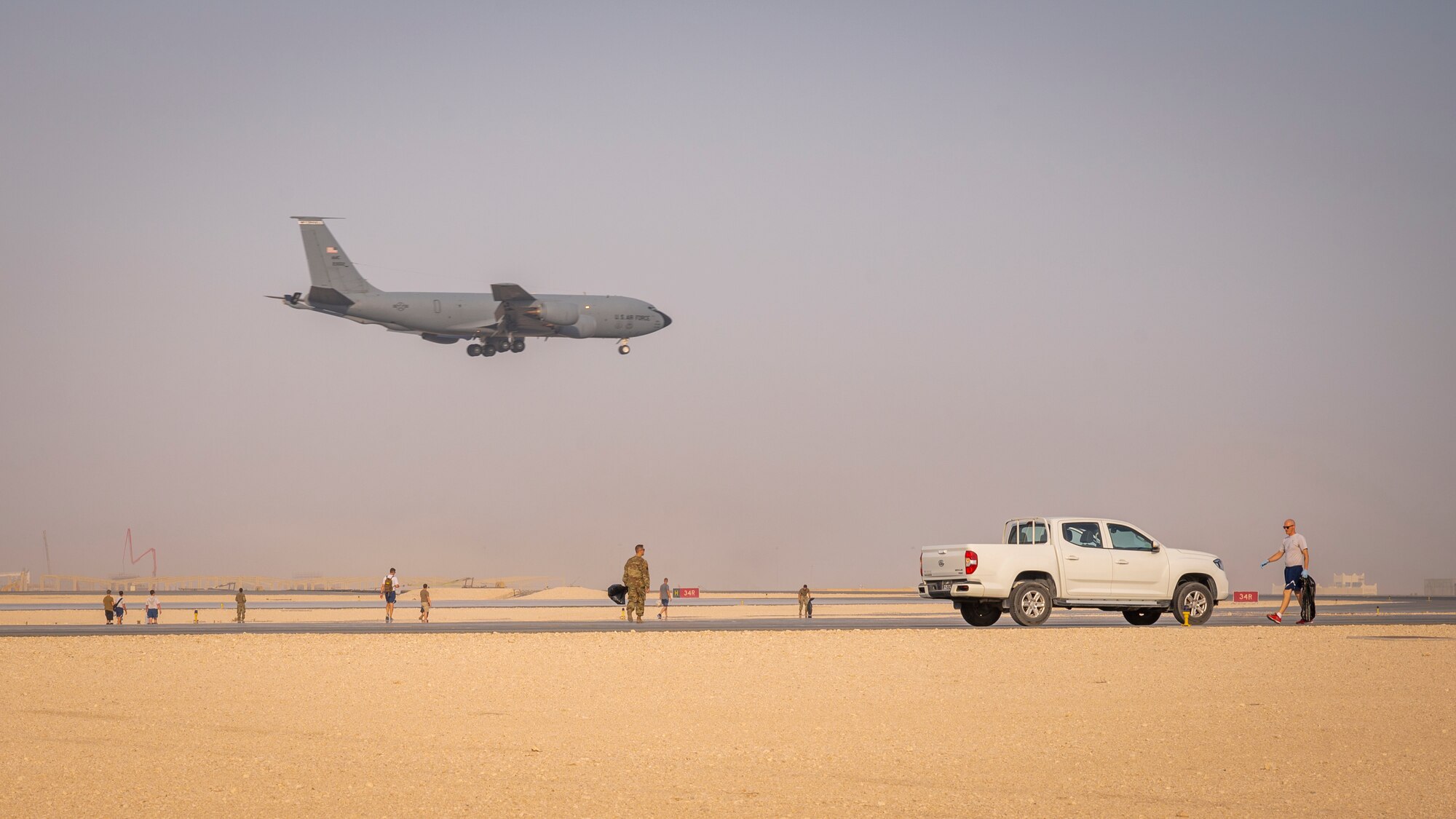 A KC-135 Stratotanker jet lands on the runway as service members conduct a foreign object debris walk Sept. 8, 2021, at Al Udeid Air Base, Qatar.