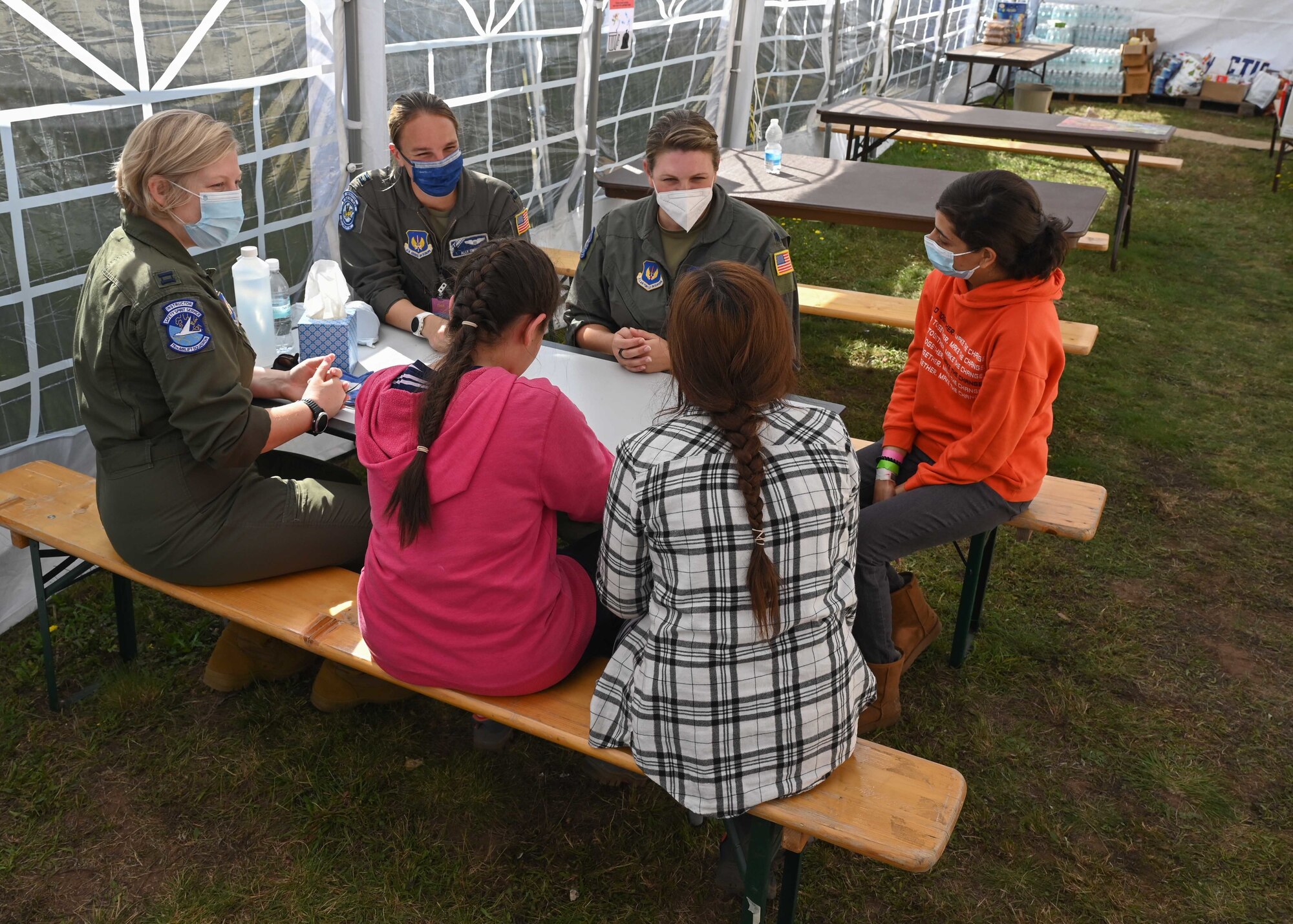 Pilots sitting at table with children.