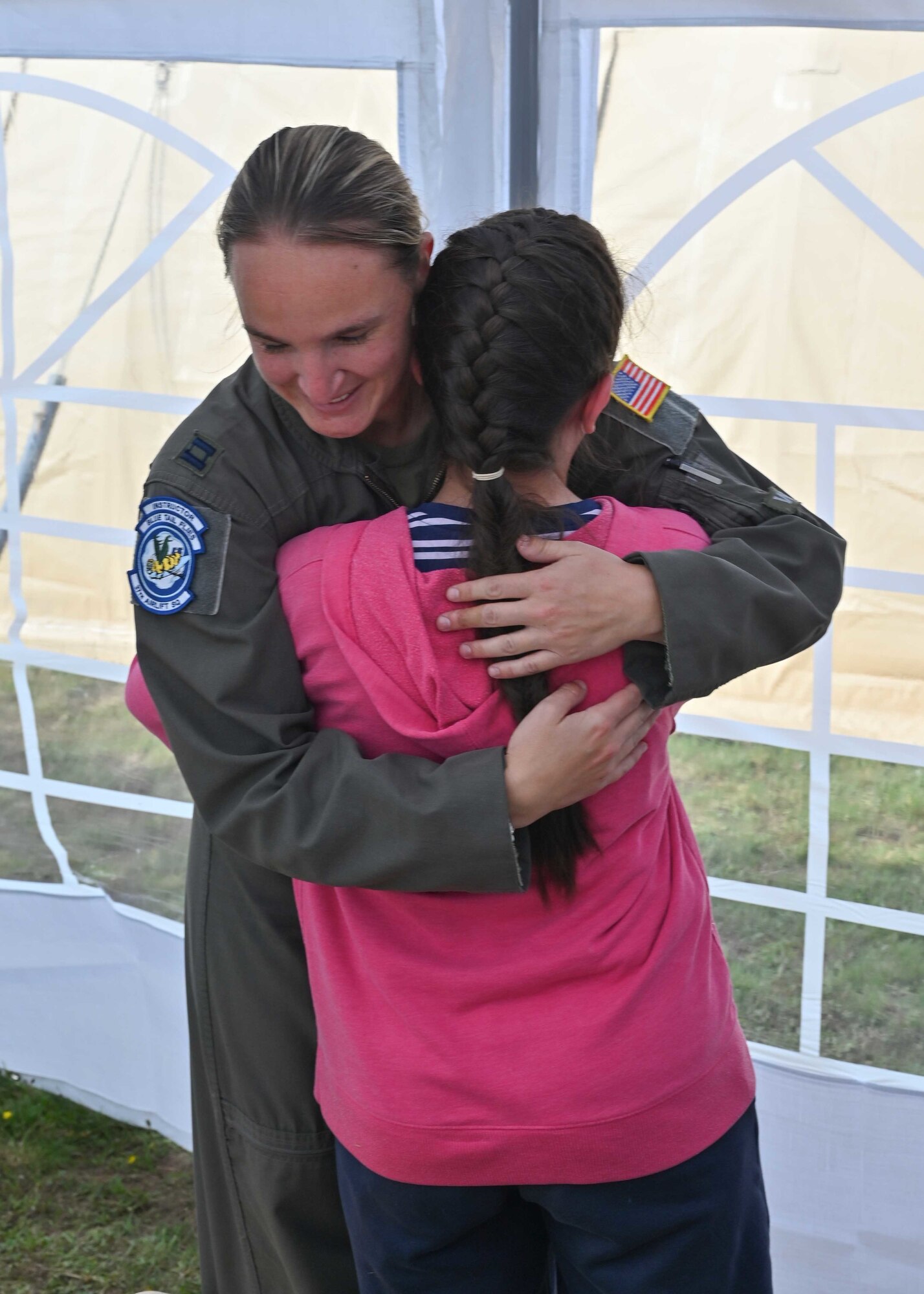 Pilot hugging young girl.