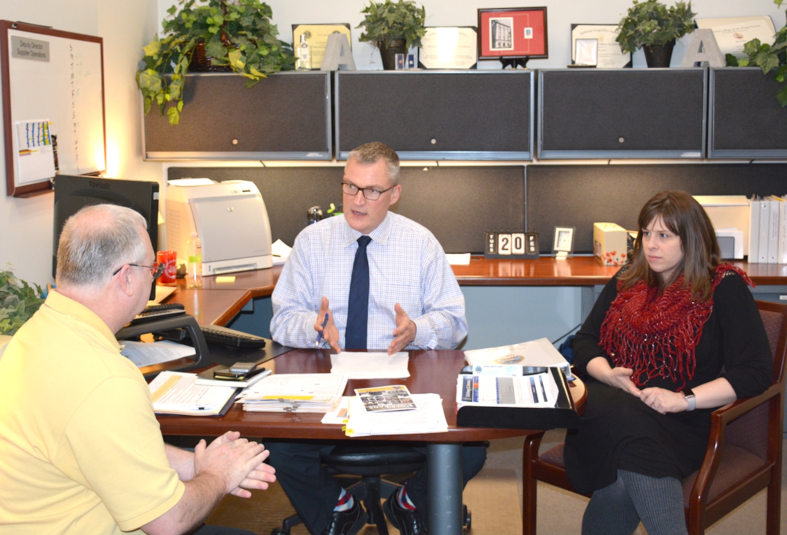 three people talking at a desk