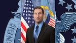 Official portrait of man sitting in front of American and DLA flags.