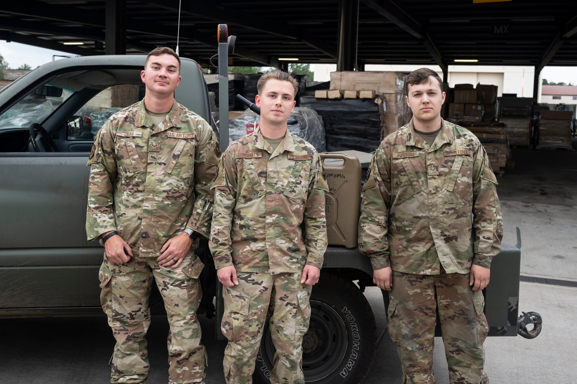 Airman pose in front of vehicle.