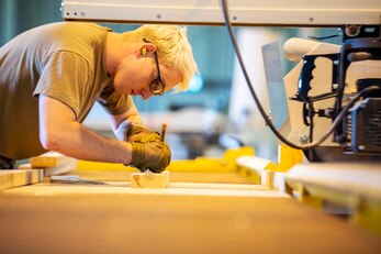 Staff Sgt. Ivan Hess, 420th Munitions Squadron conventional maintenance crew chief, writes down measurements on a block of wood at RAF Welford, England, Sept. 7, 2021. Airmen from the 420th MUNS constructed multiple wooden structures and supports to help stabilize inert assets inside an iso-container. The container was transported to RAF Lakenheath for an upcoming Agile Combat Employment exercise. (U.S. Air Force photo by Senior Airman Eugene Oliver)