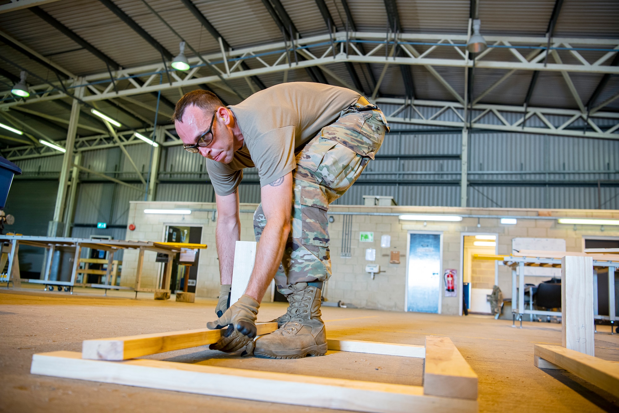 U.S. Air Force Tech. Sgt. Brandon Mullenix, 420th Munitions Squadron conventional maintenance section chief, lays down a piece of wood prior to an asset transport at RAF Welford, England, Sept. 7, 2021. Airmen from the 420th MUNS constructed multiple wooden structures and supports to help stabilize inert assets to be transported to RAF Lakenheath for an upcoming Agile Combat Employment exercise. (U.S. Air Force photo by Senior Airman Eugene Oliver)