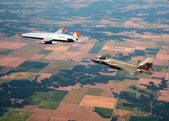 An unmanned Boeing MQ-25 T1 Stingray test aircraft, left, refuels a manned F-35 Lightning II.