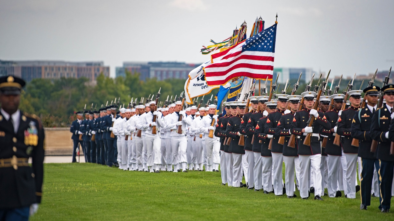Service members walk in formation on field.