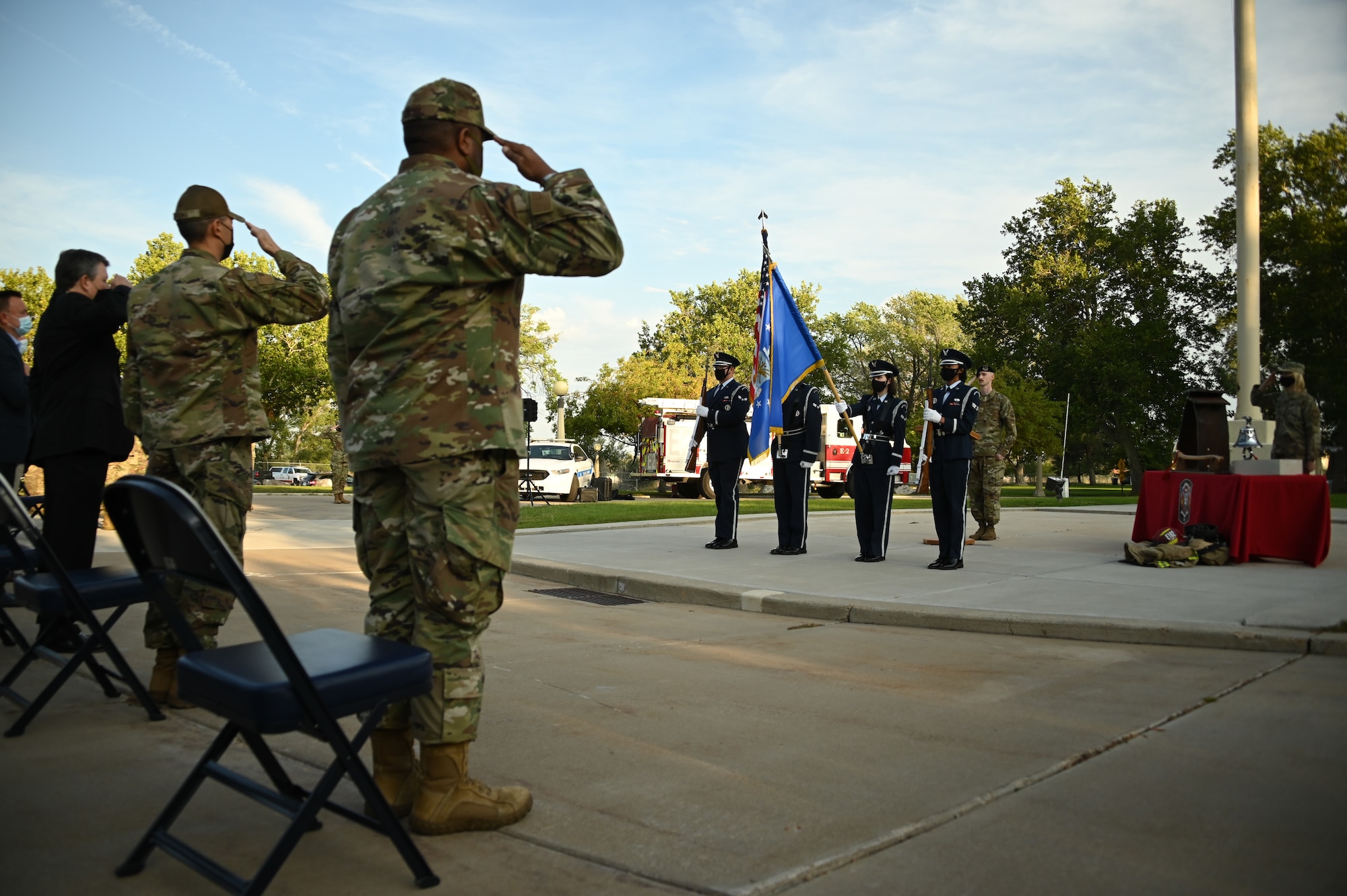 The base honor guard presents the American flag with audience members saluting in the foreground.