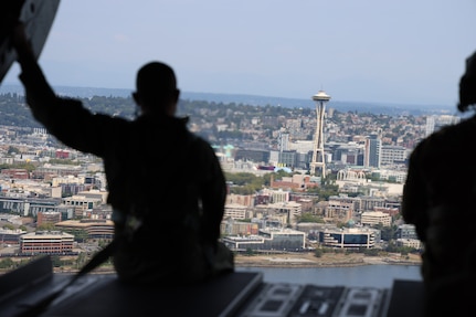 A member of the Royal Thai Army sits on the ramp of a CH-47 Chinook helicopter as it flies above Seattle, Aug. 25, 2021. The Thai Army aviators were taking part in a three-week aviation exchange with members of the Washington National Guard's 96th Aviation Troop Command.